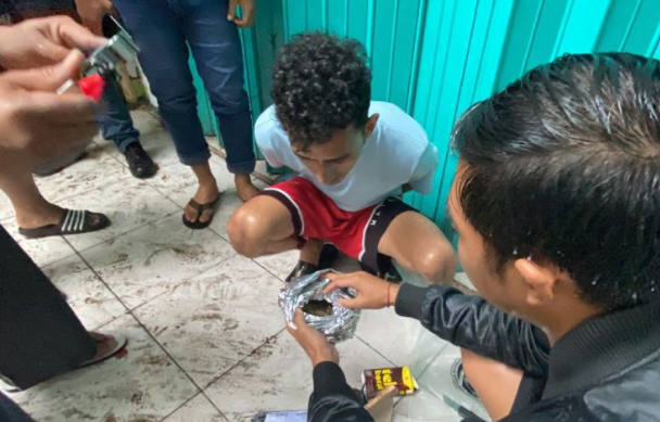 Petugas kepolisian berseragam bebas menunjukkan pelaku MFS (kedua kanan) saat menggeledah paket kiriman suku cadang kendaraan berisi ganja dalam bungkusan alumunium foil di Mataram, NTB, Rabu (3/7/2024). ANTARA/HO-Polresta Mataram.